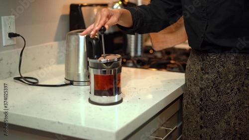 Photo of a woman who is using a French coffee maker
