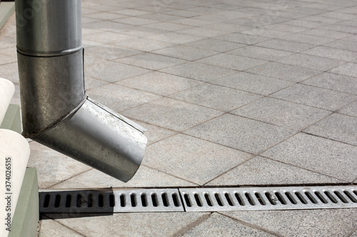 Tableau sur toile street engineering structure a downspout pipe with drainage gutter on a background of a gray stone granite sidewalk from square tiles with copy space, side view closeup nobody