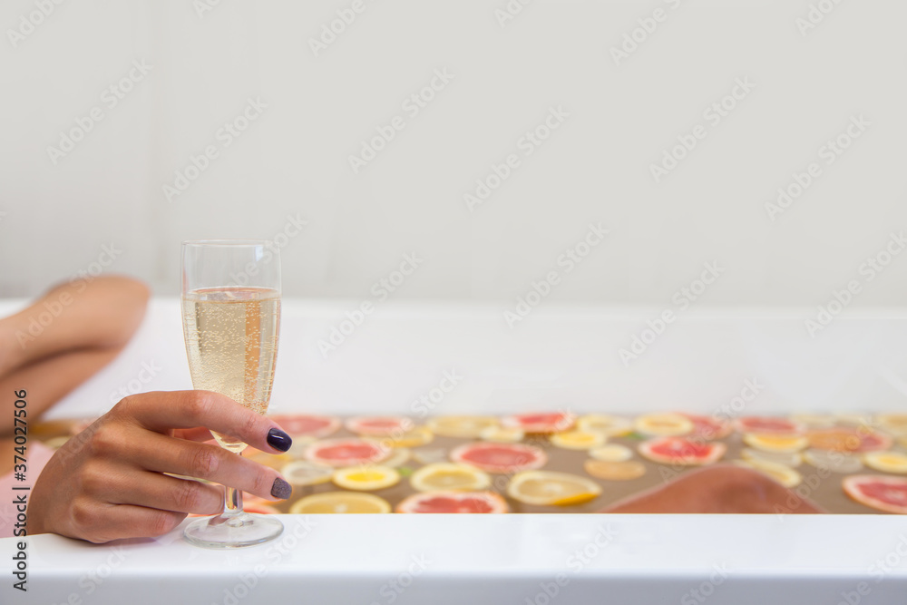 Faceless female in bathtub with slices of oranges, lemon and grapefruits. A glass of champagne. Faceless female in bathtub with slices of oranges, lemon and grapefruits. A glass of champagne.