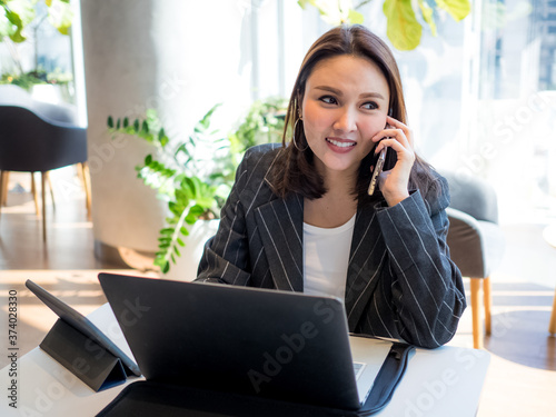 Businesswomen ceo manager company office wear suit smile beautiful is talking smartphone technology digital communication network.female is working online notebook work from home new normal 