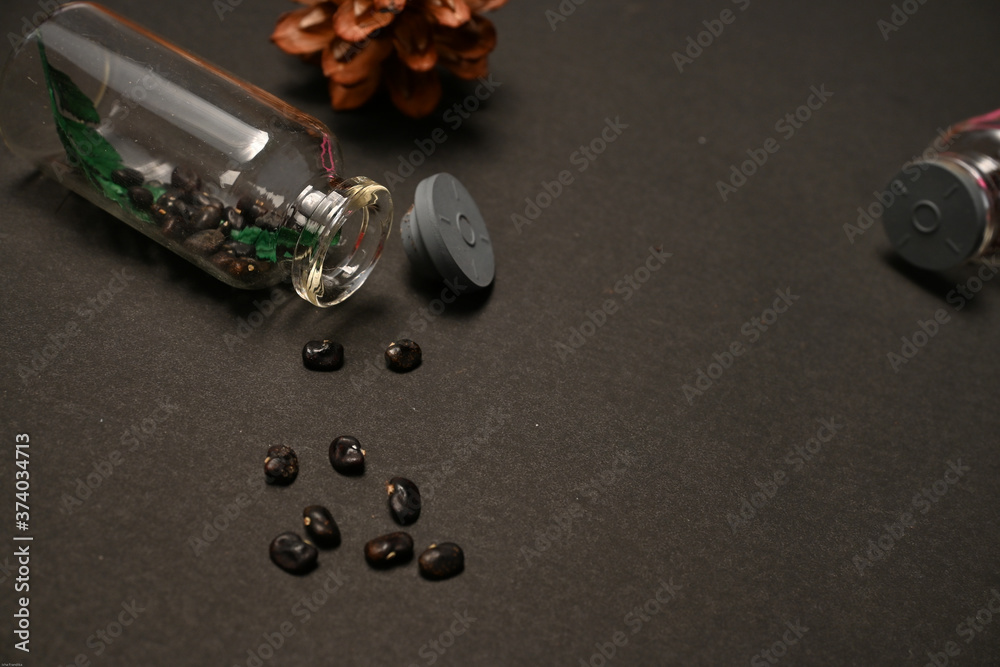 Dried seeds of telang flower ( clitoria ternatea L. ) were put inside and outside bottle isolated on black background 