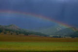 Rainbow over the mountain valley in summer. Rainbow after the rain concept