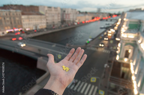 Hand with golden stars with a background of city roofs and Fontanka river