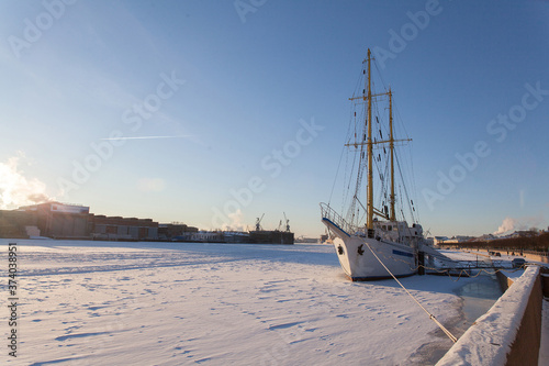 A white sailboat in the winter parking is frozen into the ice. Training ship. Saint Petersburg