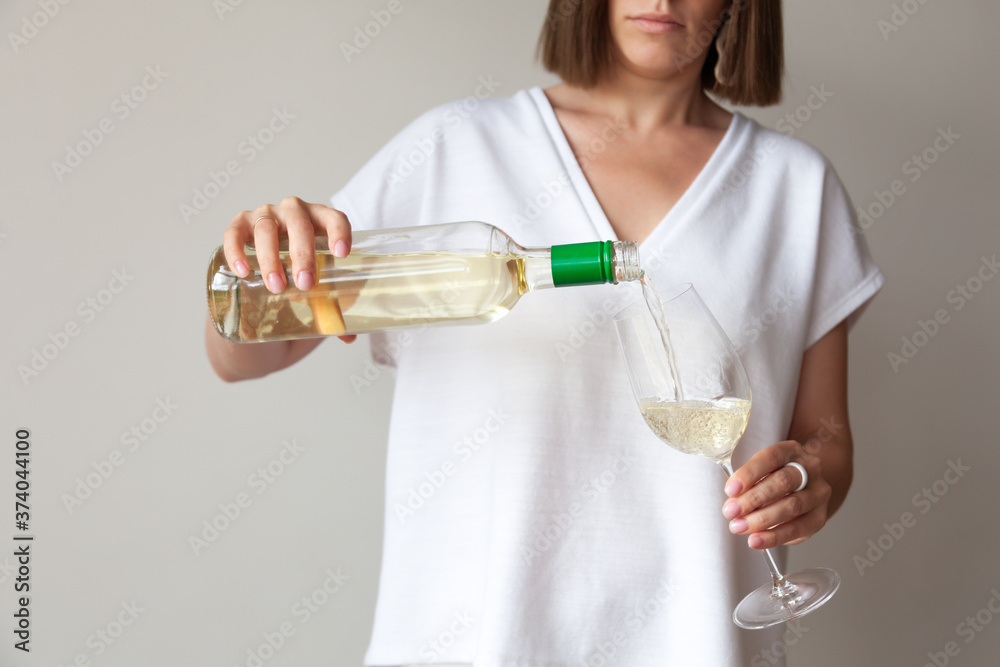 Female hands pour white wine from bottle to glass Female hands pour white wine from bottle to glass