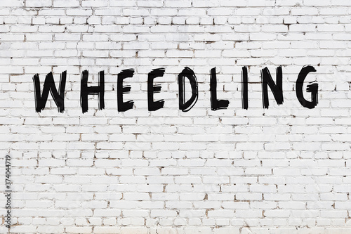 White wall with black paint inscription wheedling on it