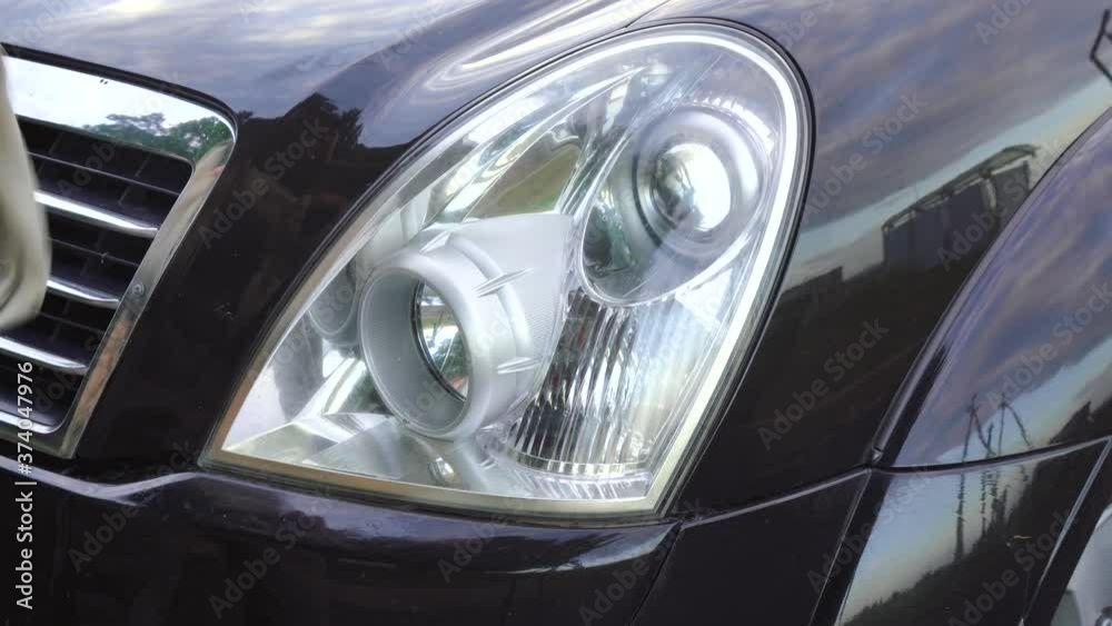 man wipes the headlight of his car man wipes the headlight of his car