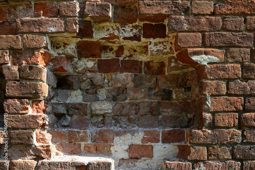 Close-up section of the old brickwork of a red brick wall  part of the wall in the center of the frame is destroyed.