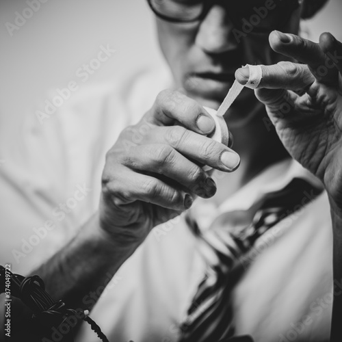 Black and white photo of Sad man applying band aid on finger after fixing broken computer in office
