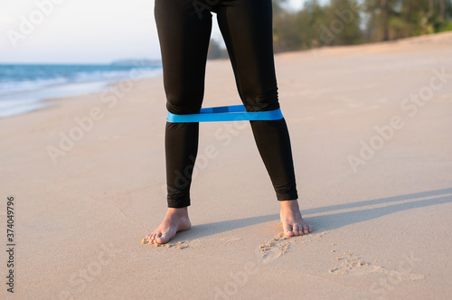 Woman using resistance band exercises for stronger legs at the beach