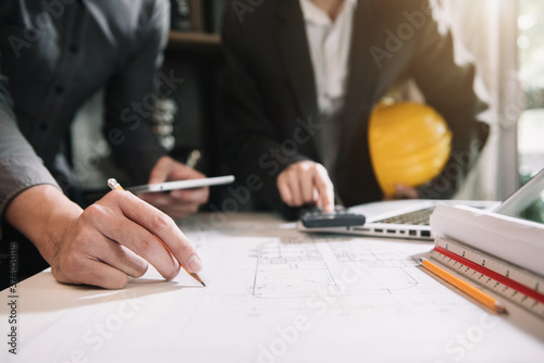 Concept architects or engineer holding pen pointing equipment architects on the desk with a blueprint in the office.