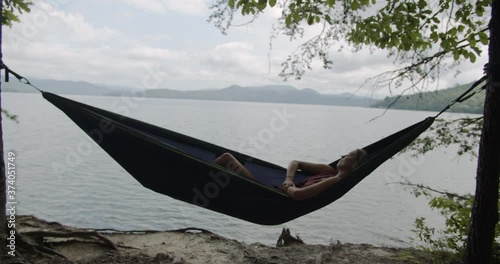 Beautiful young woman on summe rvacation lounging in hammock at Lake Jocassee in South Carolina photo