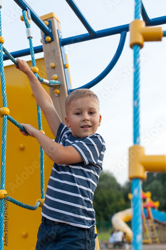 Little boy having fun on outdoor playground. Summer active sport leisure for kids. Kindergarten or school yard.