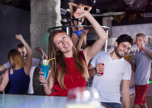 Cheerful female with cocktail clubbing in the club on party at night