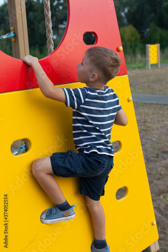 A boy climbs the wall in the Playground. rock climbing classes. Children's outdoor games