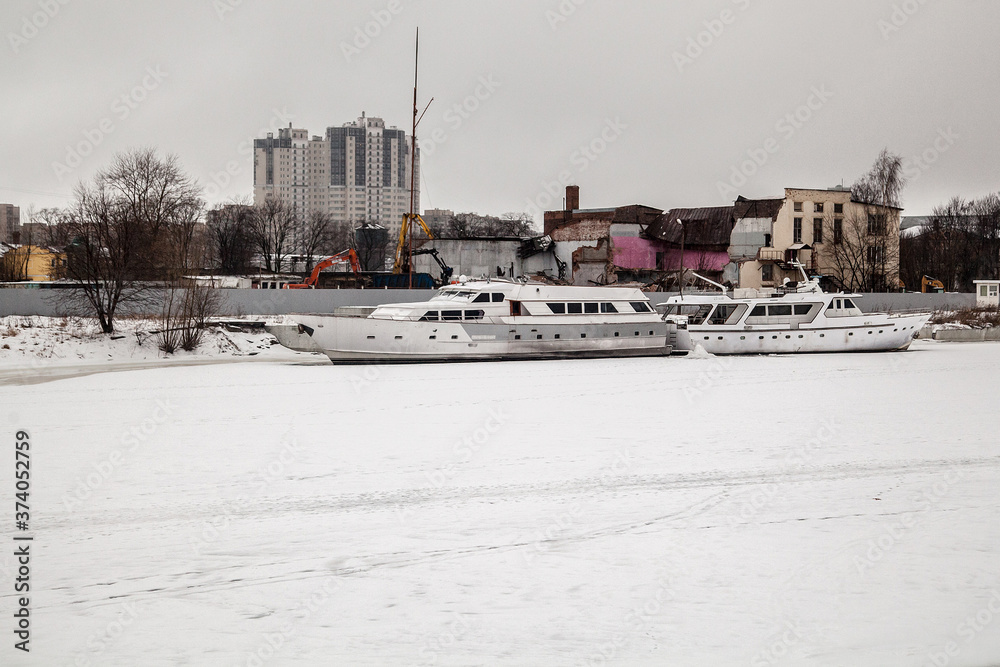 The pleasure motor ship in the winter parking is frozen into the ice