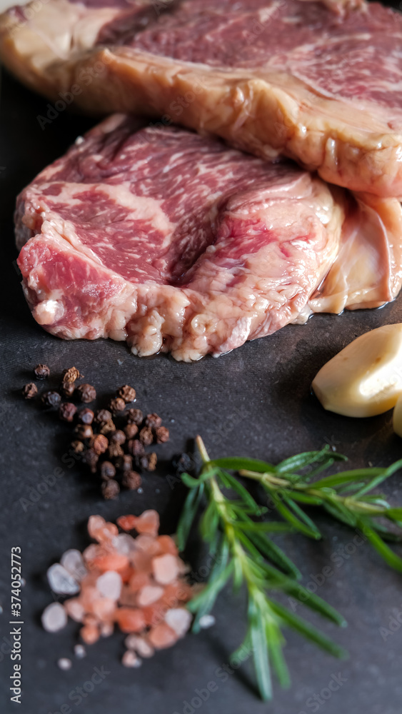 fresh slices of raw meat steak pork beef on black slate stone plate background with ingredients spices salt pepper garlic rosemary preparing and marinating barbecue meat. Healthy, natural food. fresh slices of raw meat steak pork beef on black slate stone plate background with ingredients spices salt pepper garlic rosemary preparing and marinating barbecue meat. Healthy, natural food.