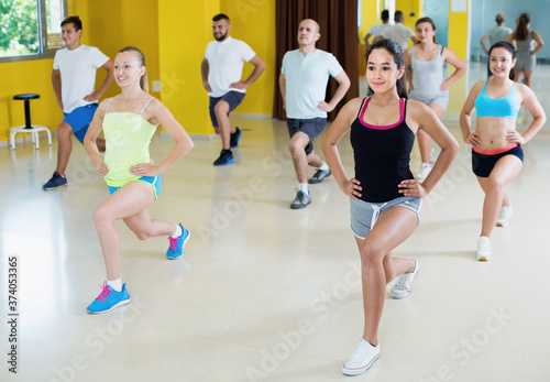 Young energy women and men dancing in fitness hall