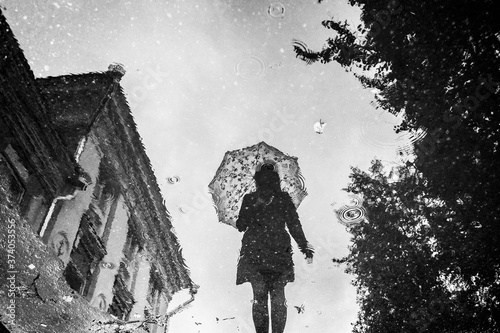 Silhouette of young girll with lace parasol reflected in puddle photo