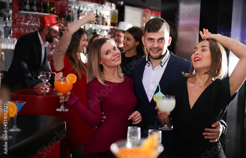 Happy young man with female friends enjoying cocktail party in bar