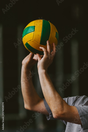 Volleyball player hands squeeze striped ball from above