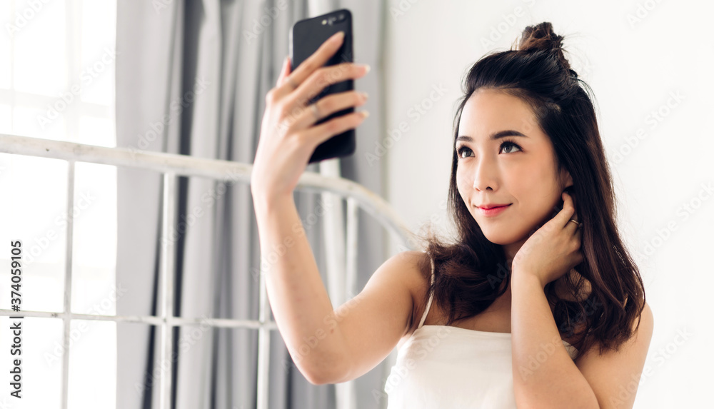 Smiling of happy cheerful beautiful pretty asian woman relaxing looking at technology of modern smartphone device.Girl felling enjoy with phone and typing text message on the bed at home.technology Smiling of happy cheerful beautiful pretty asian woman relaxing looking at technology of modern smartphone device.Girl felling enjoy with phone and typing text message on the bed at home.technology