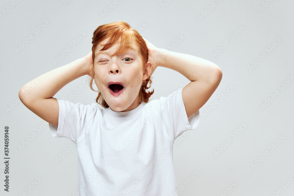Emotional red-haired boy with open mouth winks at the camera and brushes hair Emotional red-haired boy with open mouth winks at the camera and brushes hair