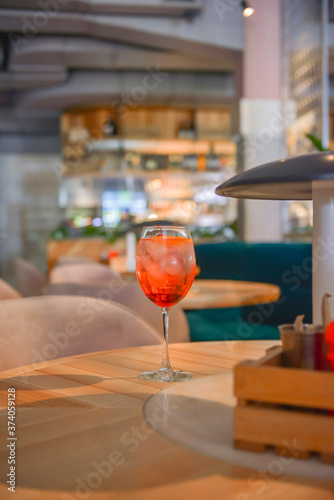 A glass with the red citrus cocktail. Alcohol summer beverage in a wine glass. Refreshing drink with ice. © zhinna
