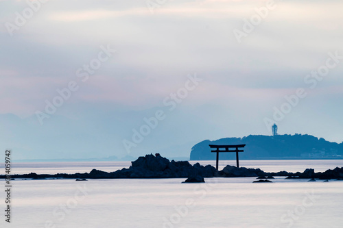 Light ray over the sea with the view of torii gate and light house in the distance photo