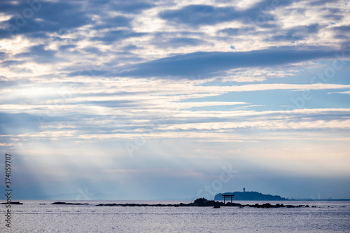 Light ray over the sea with the view of torii gate and light house in the distance photo