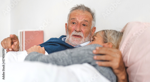 Senior happy couple relaxing and talking together lying on bed in bedroom at home.Retirement couple concept