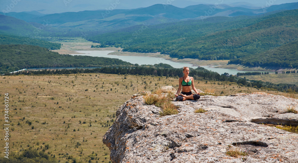 Woman in lotus position. Female meditating on fresh air.Sport and Workout. Healthy lifestyle. Green meadows view.