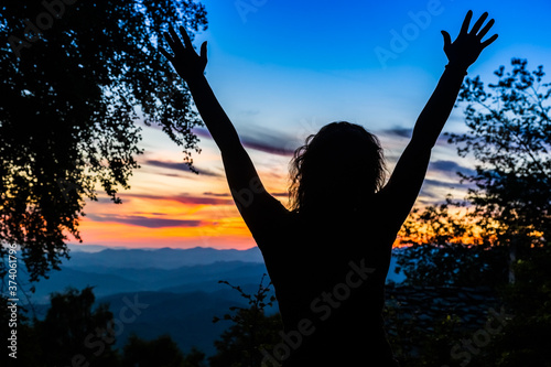Foto silhouette di donna con le braccia alzate per la felicità davanti ad un tramonto