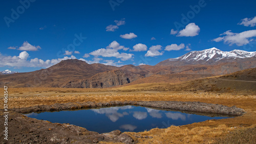 Water reserve on barren land of Spiti Valley - Blue sky with white clouds and reflection. © Abhirup