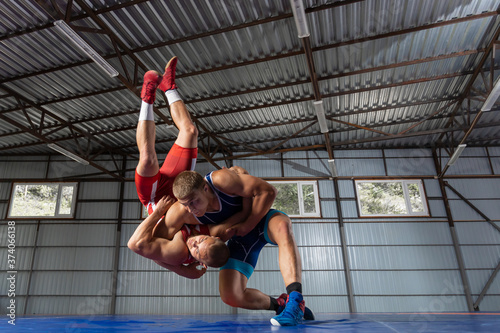 The concept of fair wrestling. Two greco-roman  wrestlers in red and blue uniform wrestling   on a wrestling carpet in the gym.