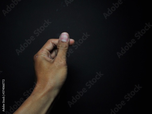 Male hand holding virtual card with fingers isolated on black background
