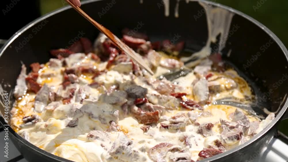 Fry pieces of meat with cream sauce in frying pan Fry pieces of meat with cream sauce in frying pan