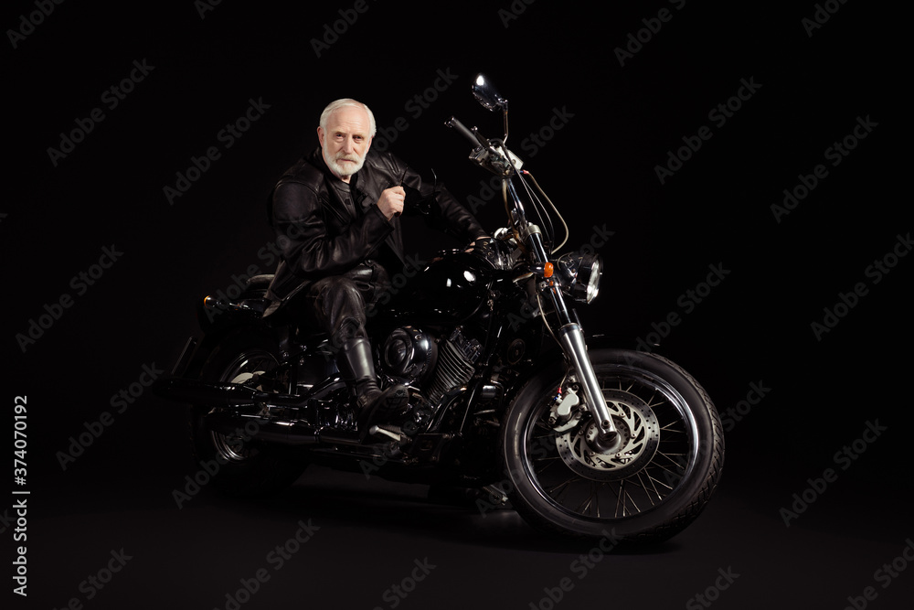 Portrait of his he nice attractive content serious grey-haired dude hipster traveler sitting on chopper spending weekend exploring world tour trip insurance isolated black color background