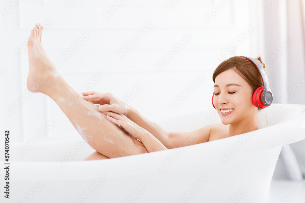 young woman with headphones relaxing in bathtub young woman with headphones relaxing in bathtub