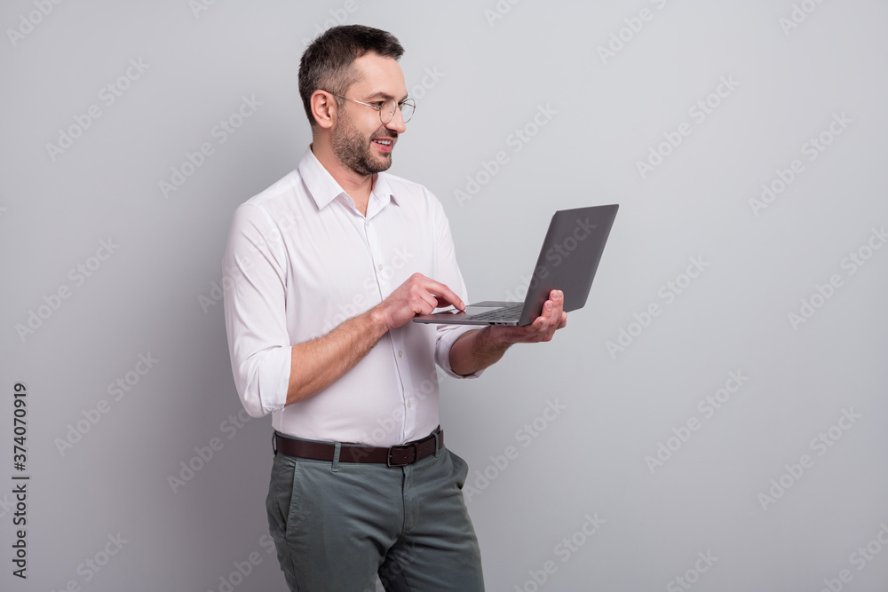 Portrait of his he nice attractive cheerful successful classy mature man holding in hands laptop preparing financial presentation report review isolated over light gray pastel color background Portrait of his he nice attractive cheerful successful classy mature man holding in hands laptop preparing financial presentation report review isolated over light gray pastel color background