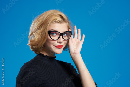 Blonde with short hair red lips glasses black jacket blue isolated background