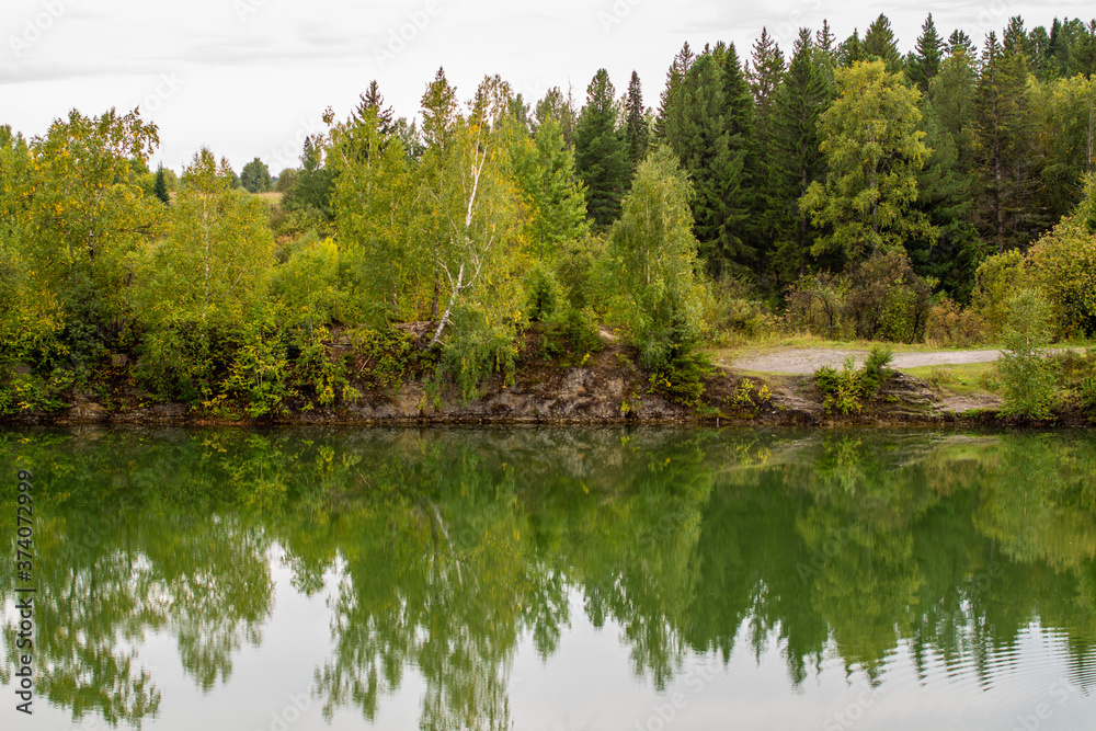 Obraz premium Stunning photo of fall foliage reflected on a lake with a glass like mirror water surface