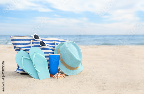 Different stylish beach objects on sand near sea  space for text