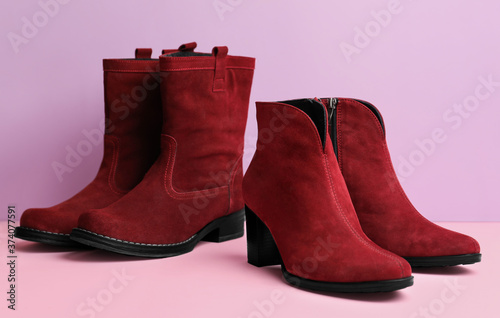 Stylish red female boots on color background
