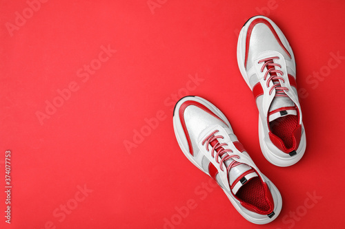 Stylish sneakers on red background, flat lay. Space for text