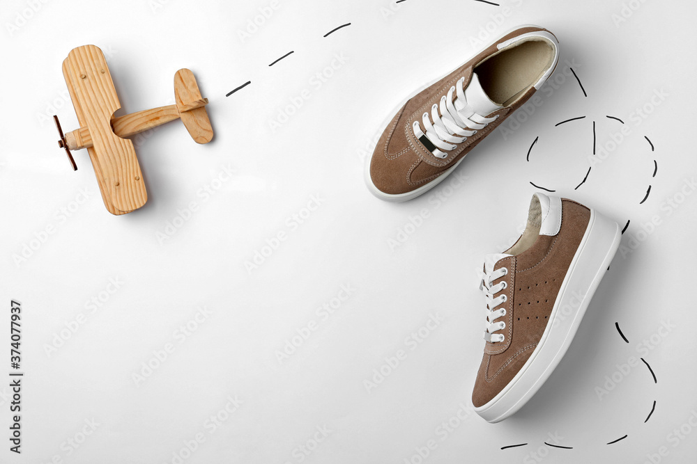 © New Africa - Stylish shoes and wooden toy plane on white background, top view