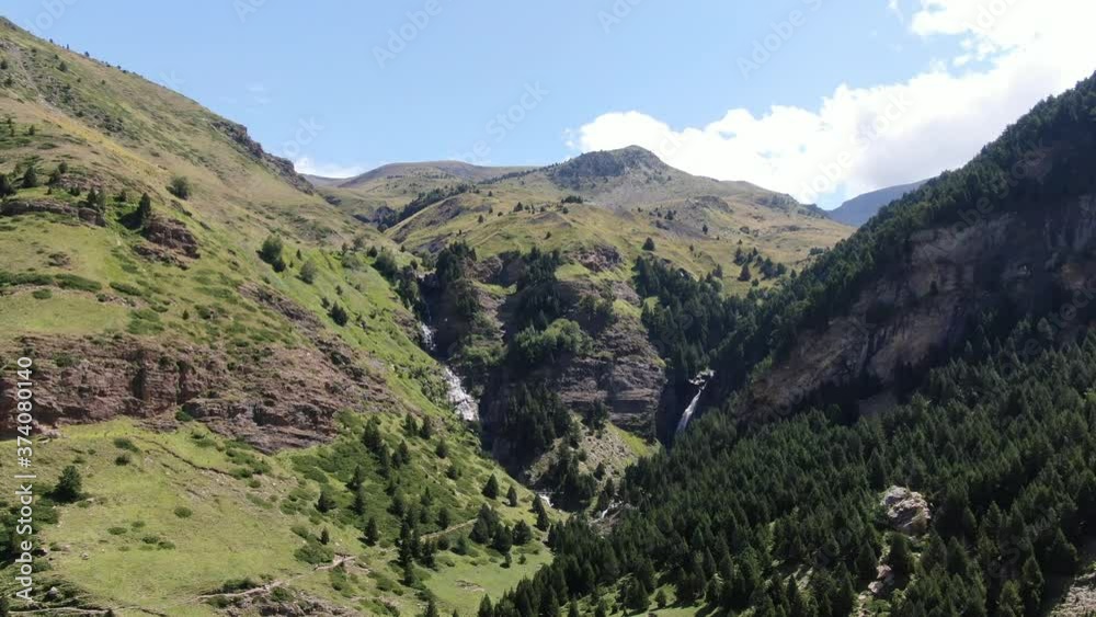 Cascada de agua en montaña con arboles y prado