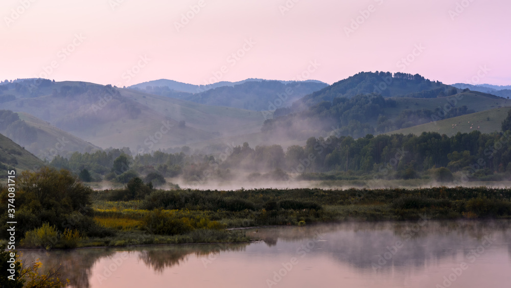 landscape in the early morning with fog over the water, mountains in the background