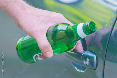 Man opening his car while holding a bottle of beer