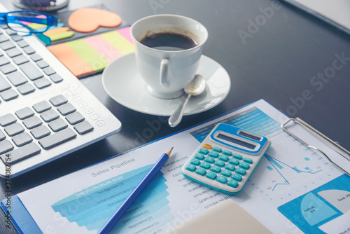 Office laptop business financial document chart and graph on wooden table with coffee cup. Flat lay notebook computer laptop on office desk. No people business graph chart mockup on business workspace